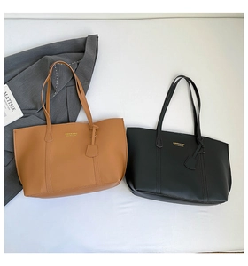 Detail of matte leather tote bags in brown and black with gold lettering logo