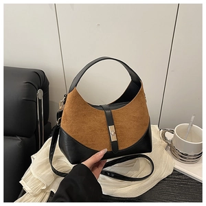 Detail of hobo bag with brown suede and black leather stitching with metal twist lock