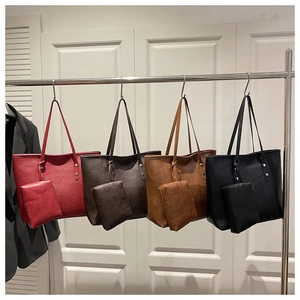 Detail view of four textured leather tote bags with matching zipper pouches in various colors