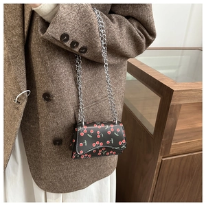 Detailansicht einer Mini-Kettentasche mit Kirschprint an einem Modell in Wollblazer