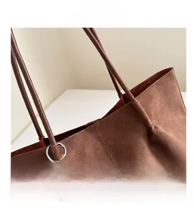 Close-up of brown suede tote bag featuring fine stitching and wood bead charm detail
