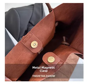 Close-up of matte gold magnetic closure on brown textured leather tote bag detail