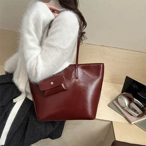 Deep red glossy faux leather tote bag set with matching inner pouch on wooden desk