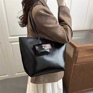 Minimalist black glossy large tote bag with matching pouch shown in a high-quality interior