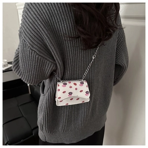 Close-up of mini crossbody bag featuring vibrant lip print and fine metal chain strap