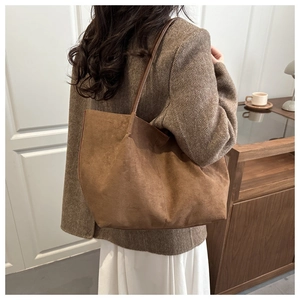 Brown vintage suede tote bag shown on shoulder with spacious design and retro texture