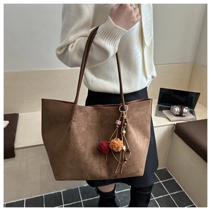 Detail of a brown suede tote bag with a decorative tassel and fine matte texture