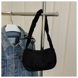 Détail d'un sac d'épaule noir en forme de croissant avec bandoulière à nœud et velours