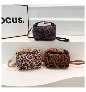 Trois sacs polochons en peluche léopard gris, beige et marron sur un socle moderne