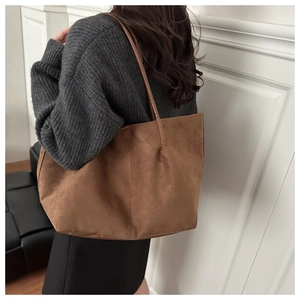 Close-up of brown suede tote bag texture with minimalist shoulder strap detail