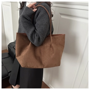 Detail view of large dark brown suede tote bag with slim shoulder straps on model