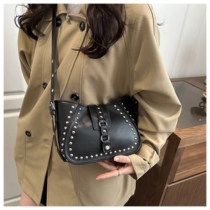 Detail of black rivet saddle bag with silver studs worn with a khaki trench coat