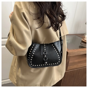 Detailed view of black rivet motorcycle saddle bag worn with a beige trench coat