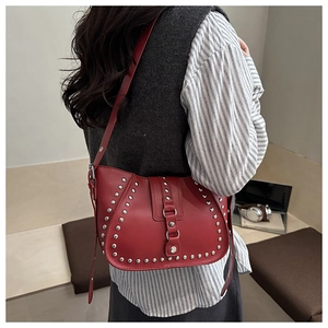 Detail of red crescent bag with silver rivet studs worn as a shoulder bag on a model