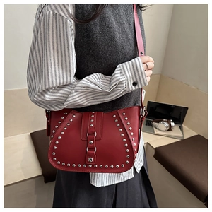 Close-up of red leather shoulder bag with silver rivet details and retro punk style
