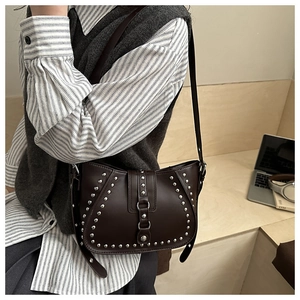 Detail of dark brown retro rivet saddle bag with silver studs and crescent leather texture