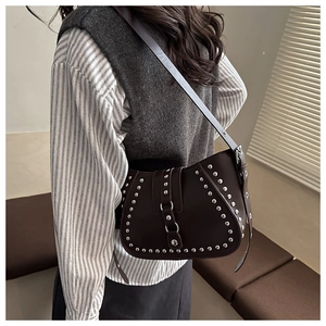 Detail of dark brown crescent bag with silver rivets and adjustable shoulder strap