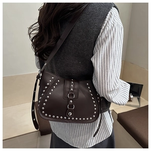 Detail of dark brown faux leather shoulder bag with silver studs and adjustable strap