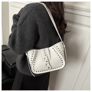 Detailed shot of white rivet shoulder bag with silver studs on textured knit sweater