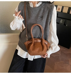 Brown suede bucket bag with leather strap and gold buckle detail shown on model