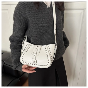 Detailed macro view of white leather shoulder bag with silver stud rivets and strap