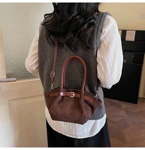 Detail of dark brown faux suede handbag with adjustable leather buckle and strap