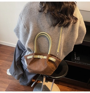 Brown suede crossbody bag with green handles shown in a lifestyle model setting