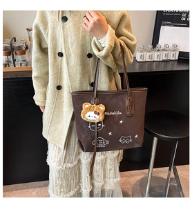 Close-up of brown tote bag with cute cat print and fluffy bear charm in coffee shop