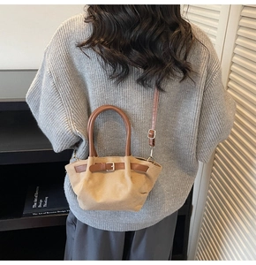 Detail of beige canvas crossbody bag with brown leather straps and buckled strap contrast