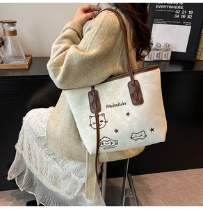 Detail van de crème tote bag met kattenprint en bruine leren riemen op het model