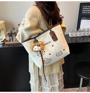 Detail of vintage tote bag with cute cat graphics and plush bear pendant on model