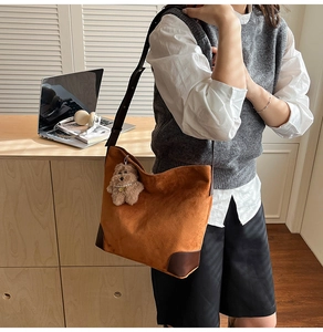 Détail du sac cabas en daim marron avec coins en cuir renforcés et pendentif ours mignon