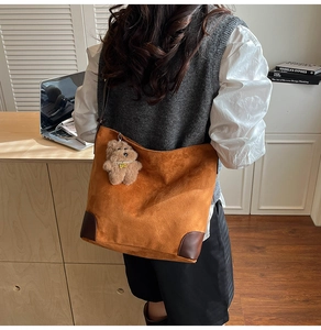Détail du sac hobo en daim avec coins en cuir renforcés et pendentif ours en peluche