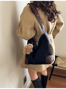 Détail du sac seau en daim noir avec finitions cuir marron et breloque ours à l'épaule