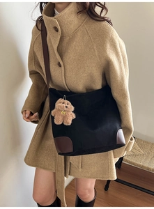 Détail du sac cabas en toile noire avec base en cuir marron et breloque ours sur modèle