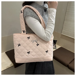 Dettaglio della borsa tote rosa trapuntata con ricamo a fiocco nero e ciondolo argento