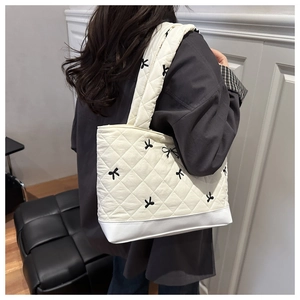 Vista dettagliata di una borsa tote trapuntata bianca con ricami a fiocco indossata