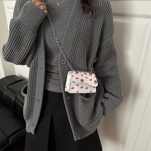 Chic white mini crossbody bag with red lip print and silver chain strap on model