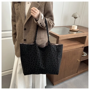 Close-up of leopard print suede tote bag worn by a model in a cozy indoor setting