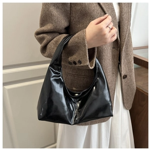 Detail of black glossy patent leather hobo bag with a soft texture for stylish women