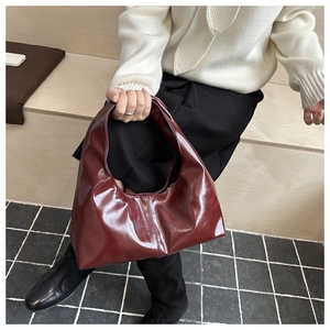 Detail of burgundy glossy patent leather tote bag with elegant vertical stitching