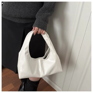 Detail of white glossy hobo shoulder bag with seamless handle and vertical stitching