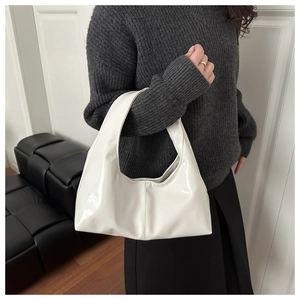 Close-up of a glossy white leather hobo bag showing minimalist stitching and modern texture