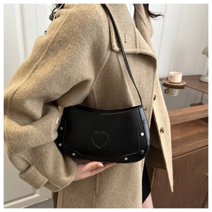 Detail of a black rivet shoulder bag with heart patch on camel wool coat outfit