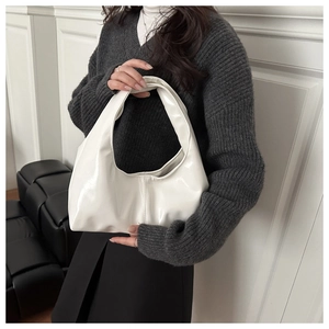 Detail view of large white glossy tote bag showing vertical stitching and smooth faux leather