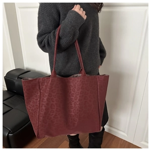 Detail of burgundy leopard print leather tote bag with long handles for shoulder wear