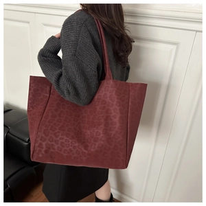 Macro detail of burgundy leopard print on faux suede tote bag with matte texture