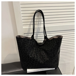 Détail du sac cabas en daim noir à motif léopard avec deux fines anses et grand volume