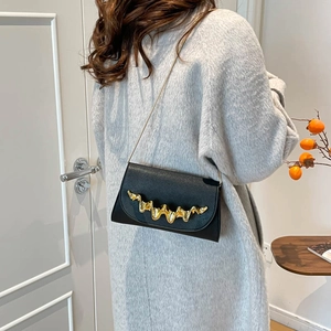 Chic black wave-textured chain bag with liquid gold metal detail worn by a model