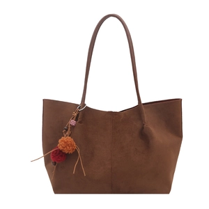 Brown faux suede tote bag with plush ball charms and spacious minimalist interior design
